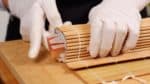 由於壽司卷的左右兩端容易鬆開，請用另一隻手握住壽司卷的同時用手指輕輕按壓兩側。