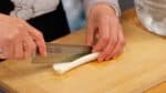 Préparez la partie blanche du poireau aussi appelé Naganegi. Coupez l'extrémité et coupez le poireau en deux dans le sens de la longueur.