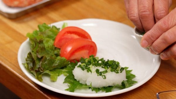 Place the grated daikon onto a shiso leaf and arrange the red leaf lettuce leaves and tomato wedges on a plate as side vegetables. Place a generous amount of chopped spring onion leaves on top of the grated daikon.