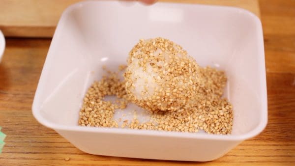 Then, coat the onigiri with half-ground sesame seeds.