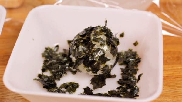 Then, coat the second onigiri with crumbled toasted nori seaweed.