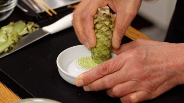 Now, let's grate the wasabi. Using the finest grater possible, grate the wasabi starting from the end with the leaf stalks attached.