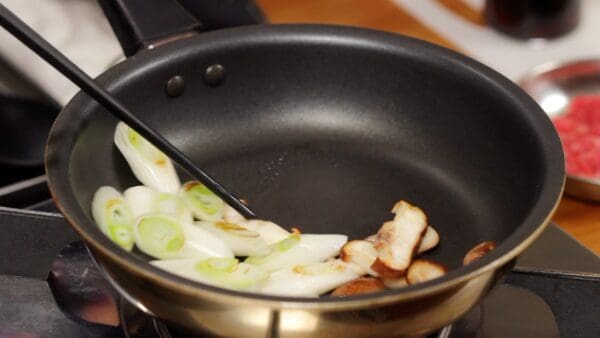 Now, turn off the heat. Turning off the heat will keep the long onion and shiitake slices from overcooking. Push the long onion and shiitake mushroom to one side to make space.