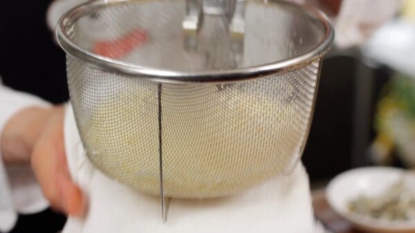 Hit the bottom of the strainer with a kitchen towel numerous times to remove the excess water.