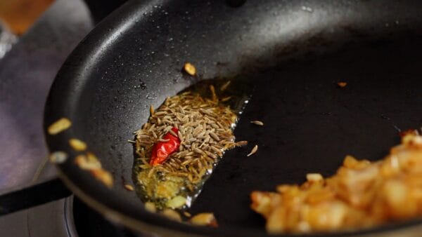 Add the cumin seeds and one third of the dried red chili pepper.