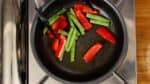 Add the string bean pods and red bell peppers.