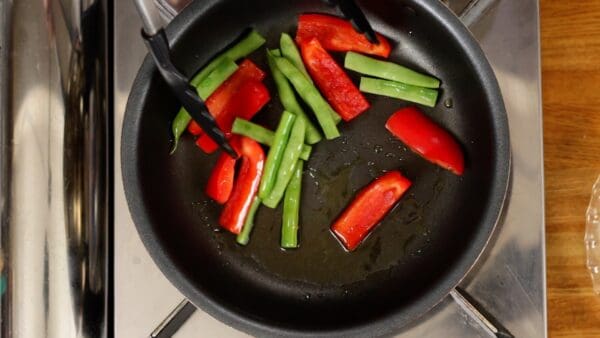Add the string bean pods and red bell peppers.