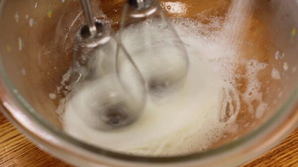 Lorsque le blanc d'œuf se casse et commence à former des bulles, ajoutez 1/3 du sucre.