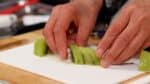Arrange 7 slices of kiwi in a row, shifting them about 5 mm (0.2") apart, and roll them together from one side to form a rose shape.