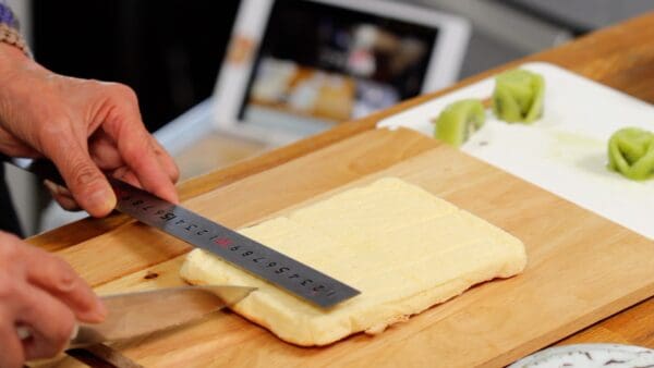 To divide the cake evenly into four squares, use a clean ruler to mark the cake in the middle.