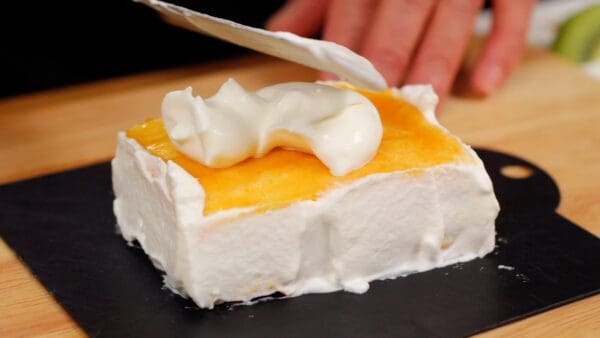 When all the sides are covered with the cream, place the whipped cream on top and spread it out.