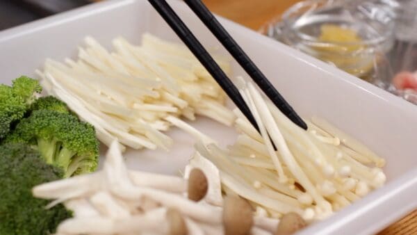 Cut off the root end of the enoki mushrooms, halve the length, and tear the lower half into smaller pieces.