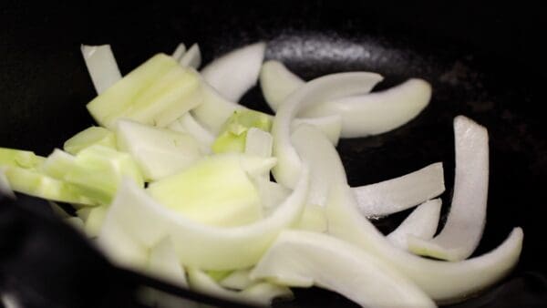 Add the sliced onion and broccoli stems. Saute on medium-low heat until the edges of the onion begin to brown slightly.