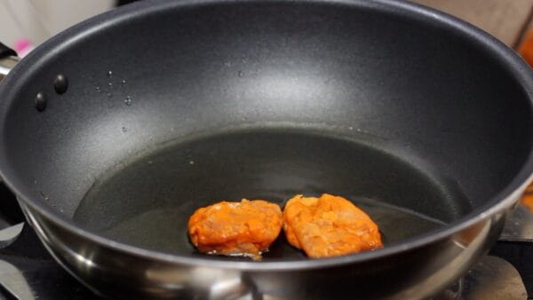 Let's make the chicken karaage! Heat 3 mm (0.12") of vegetable oil in a frying pan over medium heat. When the oil is heated and it becomes less viscous, add the meat, starting with the largest pieces first.