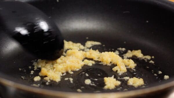 Verwarm de sesamolie in een koekenpan, en voeg de geraspte gember en knoflook toe. Fruit dit even aan.