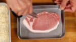 Laten we de tonkatsu bereiden. Dit is een Japans gepaneerd filetlapje. Gebruik een keukenschaar om meerdere inkepingen te maken in het taaie, draderige gedeelte tussen het vet en het magere vlees in het filetlapje. 