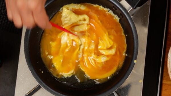 The egg around the edges of the pan will quickly puff up. Use a spatula to gather the egg towards the center, making sure that the entire mixture is half-cooked.
