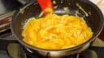 Lorsque la surface de l'œuf est encore douce et soyeuse, retirez la casserole du feu et placez l'œuf sur le riz dans un bol.