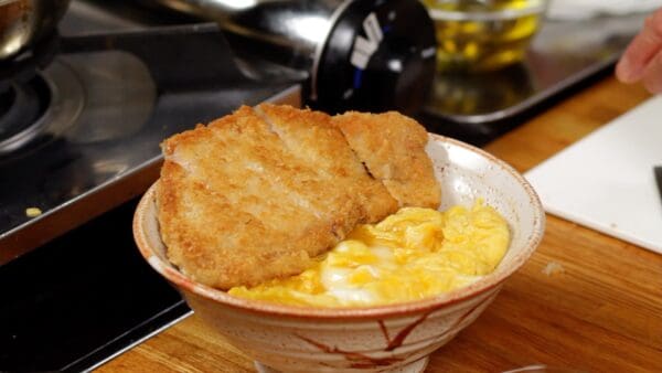 Place the tonkatsu on top of the egg. Arrange the tonkatsu pieces to make their cross-sections look visually appealing.