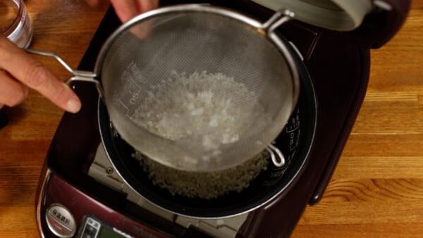 Now, let's cook the Salmon Takikomi Gohan. Place the rinsed rice into the rice cooker.