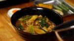 Versez généreusement le bouillon de curry chaud et savoureux sur les udon.