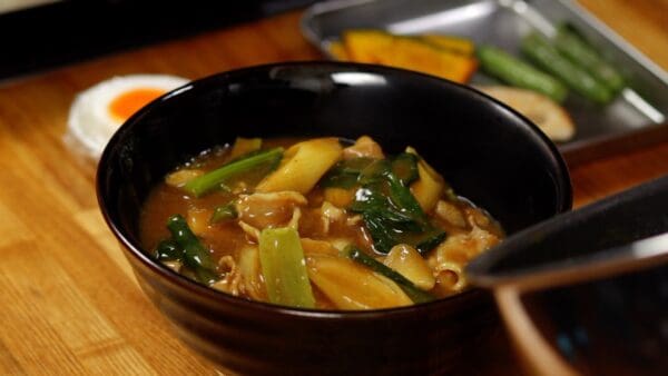 Ladle the hot, savory curry broth generously over the udon.