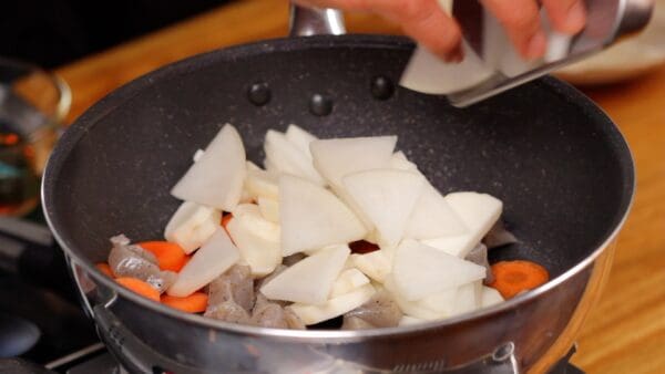 Add the carrot slices, parboiled konjac, taro, and daikon radish.