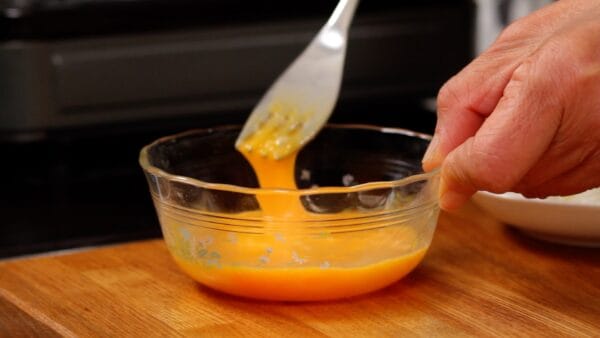 Now, let's make Natto Chahan. Add the vegetable oil to a frying pan and heat it up. Beat the egg thoroughly with a fork.