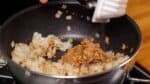 Once the rice grains are somewhat separated, gather them to one side to create a space for adding the natto, or fermented soybeans. Stir-fry the natto directly on the pan.