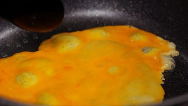 To check if the frying pan is hot enough, drop in a bit of the egg mixture. Once you hear a sizzling sound and the pan is hot enough, pour in the egg mixture.