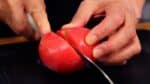 Now, meet our star ingredient – the frozen tomato! This has been soaking in water for 3-4 minutes. It's best to soak it right before boiling the pasta. Cut the tomato in half.