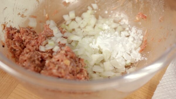 肉をずらしボウルに隙間を作ります。隙間に玉ねぎのみじん切りを加えます。